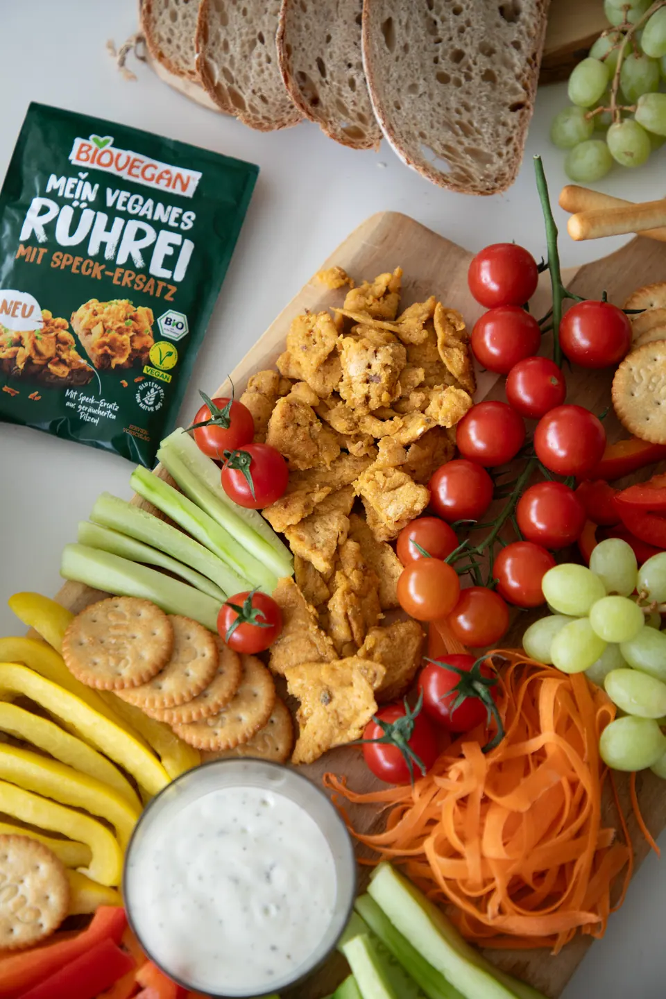 Biovegan-Rührei-Alternative mit Produktpackung und angerichtetem Snackboard