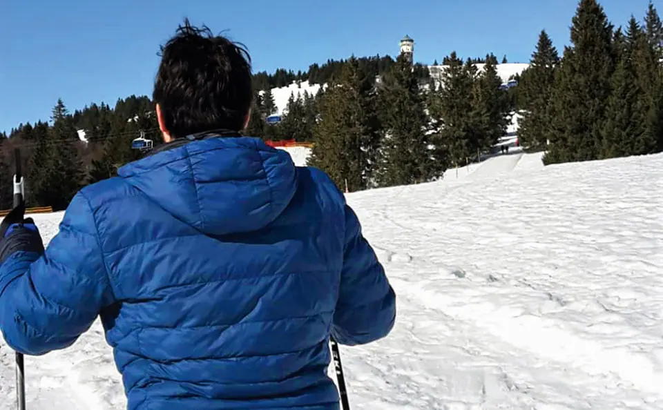 Person in blauer Jacke an einer verschneiten Landschaft