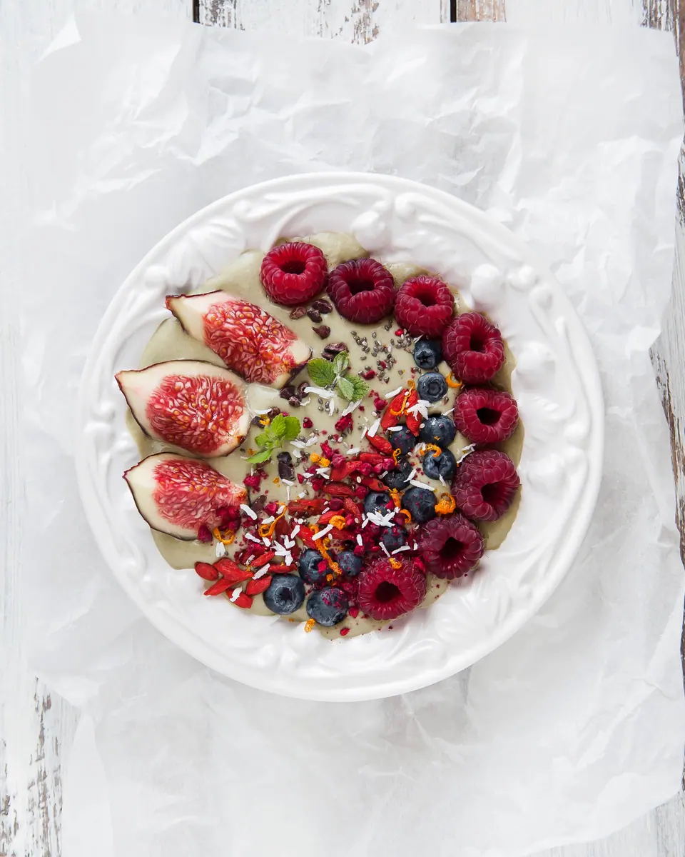 Smoothie-Bowl mit Beeren und weiteren Toppings auf hellem Untergrund